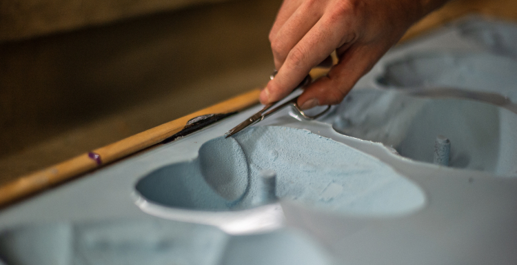 A Proxy employee trimming excess silicone from a climbing hold mold.